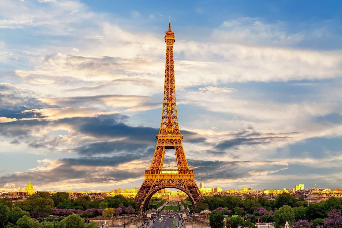 Der Eiffelturm in Paris in goldener Farbe bei bewölktem Tageshimmel